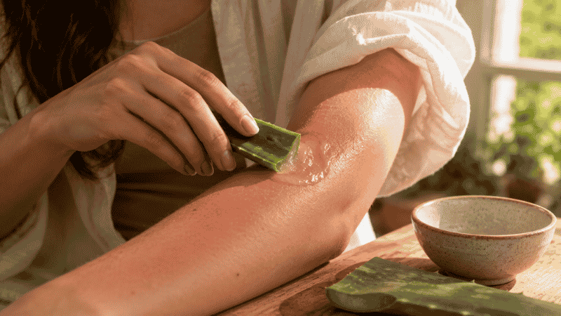 A person applying fresh aloe vera gel from a cut leaf onto their skin — aloe vera gel is scientifically proven to accelerate healing of minor burns and sunburn